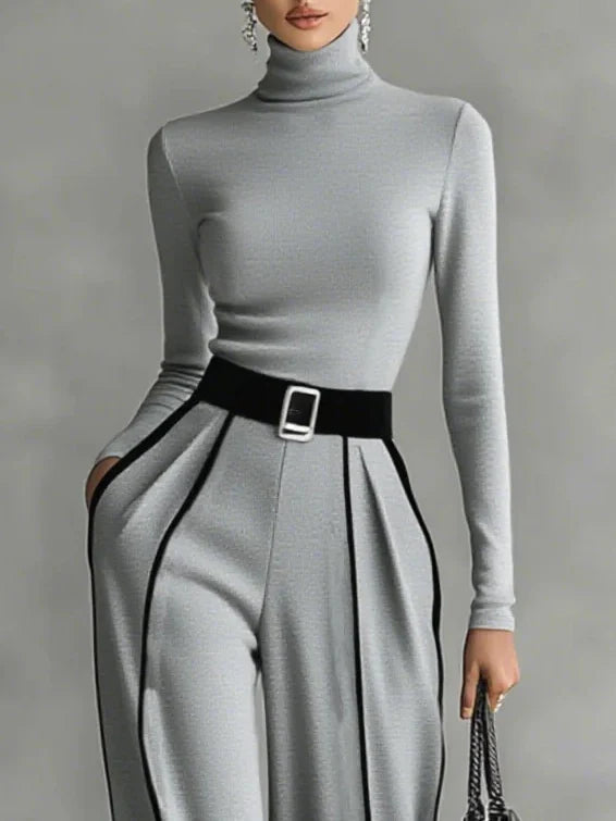 Conjunto de top blanco de cuello alto y manga larga con pantalones de pierna ancha y cinturón.