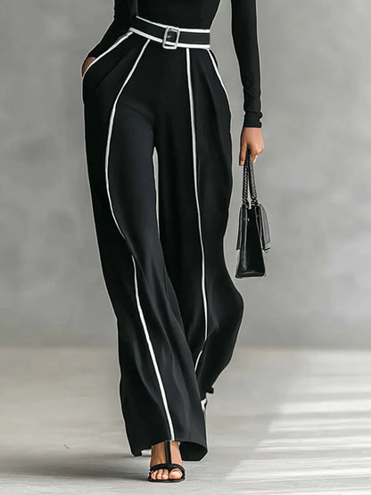 Conjunto de top blanco de cuello alto y manga larga con pantalones de pierna ancha y cinturón.