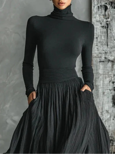 Ensemble mode : T-shirt noir moulant à col roulé et jupe plissée.